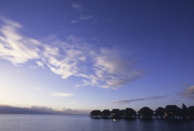 Su üzerinde bungalovları olan güzel bir gün batımı