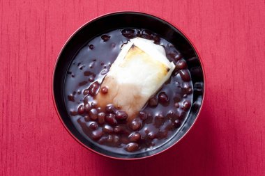 Pembe arka planda bir kase kırmızı fasulye çorbası.