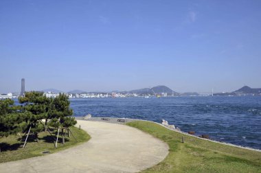 Sakin mavi suyun yanında dolambaçlı yol berrak gökyüzü altında