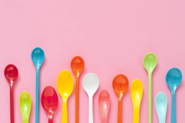 Pembe arka planda renkli plastik çatal bıçak seti. en üstteki görünüm     