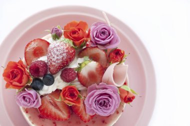 Meyve ve çiçeklerle süslenmiş lezzetli doğum günü pastasına yakın.