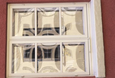 Kırmızı duvara geometrik desenleri yansıtan dikdörtgen pencere