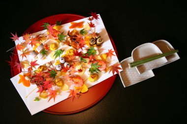 Sonbahar yapraklarıyla süslenmiş renkli Japon yemekleri.