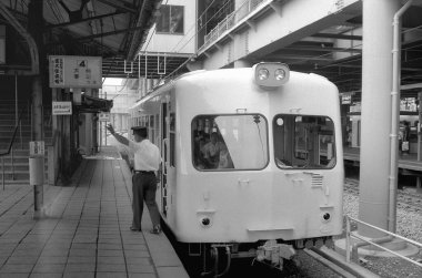 Yolcu treninin yer aldığı bir kamu istasyonunun siyah beyaz fotoğrafı.