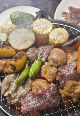 Japon restoranındaki ızgarada et ve sebze pişiren kişinin yakın çekim görüntüsü 