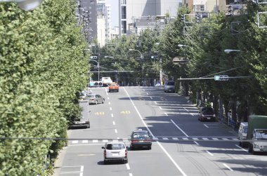 Hareket halindeki arabalar yüksek şehir binalarının yanından geçiyor.