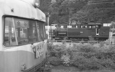 Tren raylarında giden bir trenin siyah beyaz fotoğrafı..