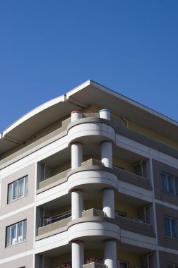 Açık mavi gökyüzüne karşı balkonları olan modern apartman binası