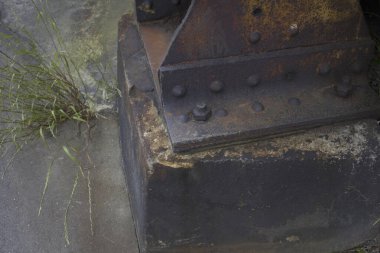 Islak beton ve çimenlerin yanında paslanmış metal kiriş tabanı