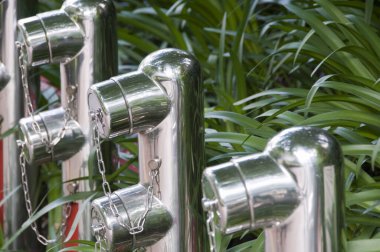 Yeşil yapraklı bitkilerin arasında duran parlak metal direkler.