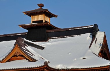 Geleneksel Japon çatısı mavi gökyüzünün altında taze beyaz karla kaplı.