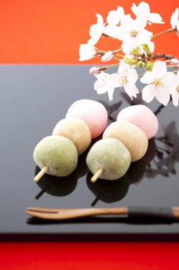Japon Mochi. Lezzetli yuvarlak tatlılar çiçekler, taç yaprakları ve ahşap çatalla servis edilir. 