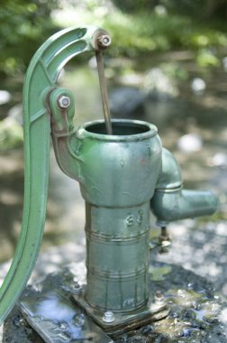 Kaliteli metal su pompası sığ akarsuyun yanında duruyor.