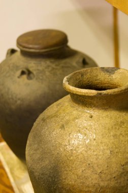 Yakın plan, iki kırsal seramik kavanozun kapalı alanda yan yana oturduğunu gösteriyor.