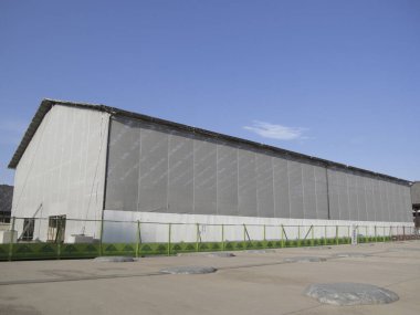 Açık mavi gökyüzünün altındaki büyük sanayi deposu.