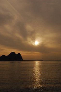 Gün batımı gökyüzü, deniz ve kayalık ada 