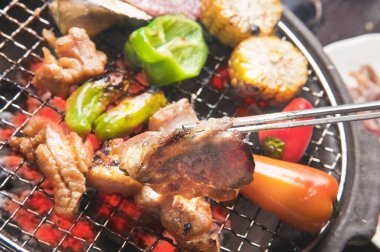 Japon restoranındaki ızgarada et ve sebze pişiren kişinin yakın çekim görüntüsü 