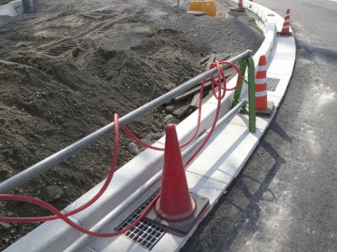 İnşaat alanının yanında turuncu trafik konileri kıvrımlı kaldırımda diziliyor