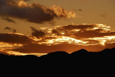 Karanlık tepeler üzerinde güzel gün batımı gökyüzü olan muhteşem manzara.       
