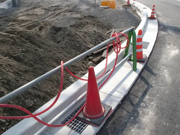 İnşaat alanının yanında turuncu trafik konileri kıvrımlı kaldırımda diziliyor