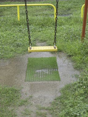 Yağmurlu bir günde boş metal salıncaklı oyun parkı