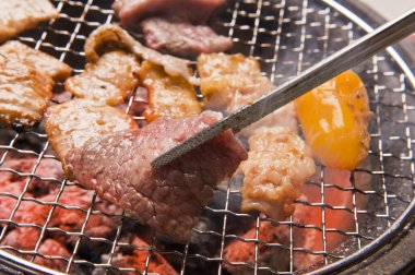 Japon restoranındaki ızgarada et ve sebze pişiren kişinin yakın çekim görüntüsü 