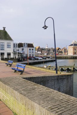 Eski binaların yakınındaki sakin limana bakan boş mavi banklar