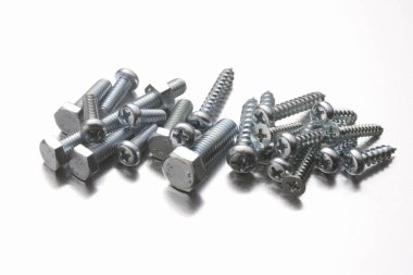 Beyaz arkaplanda metal cıvataların ve fındıkların yakın plan görüntüsü.                