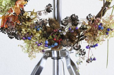 Ortanca çiçekleriyle süslenmiş çelenk ve metal bir stantta asılı diğer bitkiler.