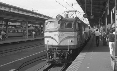 Yolcu treninin yer aldığı bir kamu istasyonunun siyah beyaz fotoğrafı.