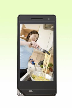 Bir kadın akıllı telefon ekranında mutfakta makarna yapıyor. 