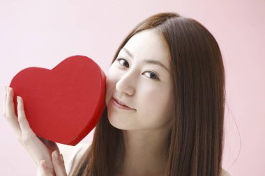 Kırmızı kalpli genç Asyalı kadın.