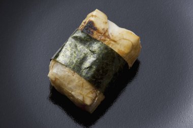 Japon suşisi fotokopi alanı olan siyah taştan bir zemin üzerinde yuvarlanıyor..