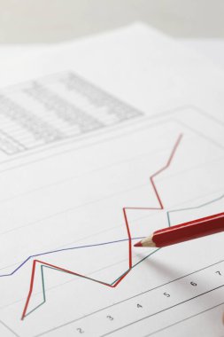 Finans grafikleri ve sayısal verileri inceleyen iş adamlarının yakın çekim görüntüleri, yatırım ve mali analizleri vurguluyor