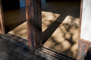 Güneş ışığı, geleneksel tatami döşeme üzerinde yumuşak gölgeler bırakıyor.