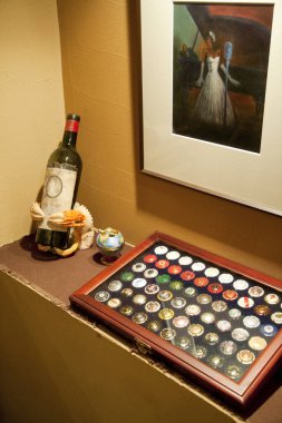 Şarap şişesinin ve resmin yanında renkli iğneler sergiliyor