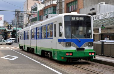 Bir Japon şehrinin göbeğindeki banliyö treni modern platformu hızla geçiyor..