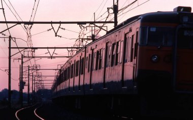 Tren Japonya 'da gün batımında demiryolunda hareket ediyor.