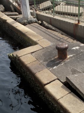 Sakin karanlık suyun yanında eskimiş beton iskele köşesi