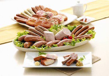 Çeşitli sosisler ve tabakta etler.