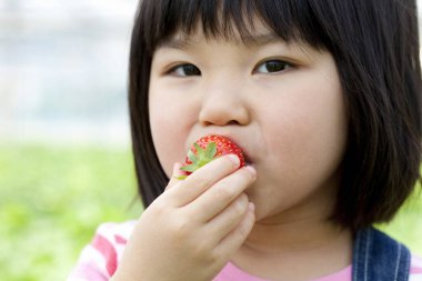 Küçük kız çilek yiyor.