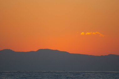 Gün batımında deniz üzerinde turuncu gökyüzü manzarası 