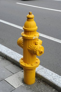 Sarı yangın musluğu şehir kaldırımının yanında duruyor.