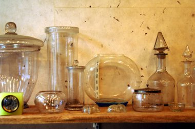 Masanın üzerinde eski cam şişeler ve mataralar var.