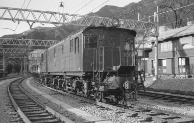 Yolcu treni, parlak gökyüzünün altında Japon demiryolu sahnesinin ön planına hakim..