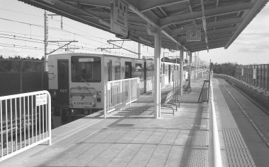 Yolcu treni, parlak gökyüzünün altında Japon demiryolu sahnesinin ön planına hakim..