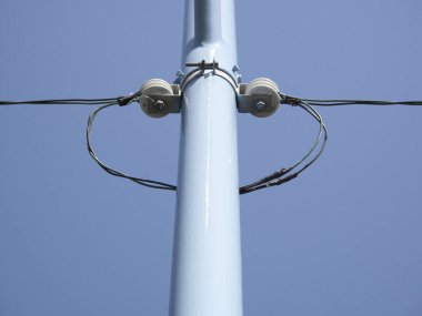 Mavi gökyüzüne karşı elektrik direğinin düşük açılı görüntüsü.         