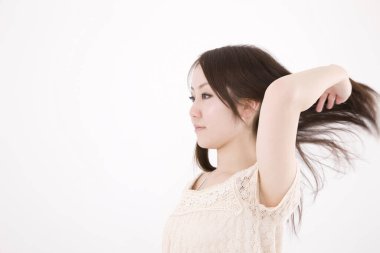 Güzel Asyalı bir kadının açık arkaplanda saçına dokunuşunun yakın plan çekimi.