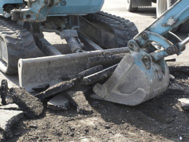 Yol inşaatı sırasında asfaltı kıran kazıcı açık havada.