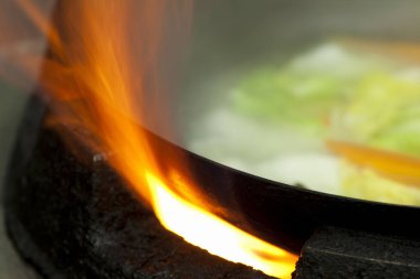 Tavada yanan sebzelerin yanında alevler yükseliyor.